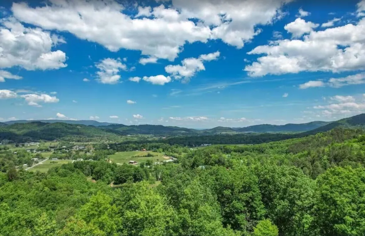 A breathtaking view of the surrounding mountain range, open fields, and expansive blue sky. The landscape is ideal for guests seeking outdoor adventures like hiking, picnicking, or simply enjoying nature's beauty in any season.
