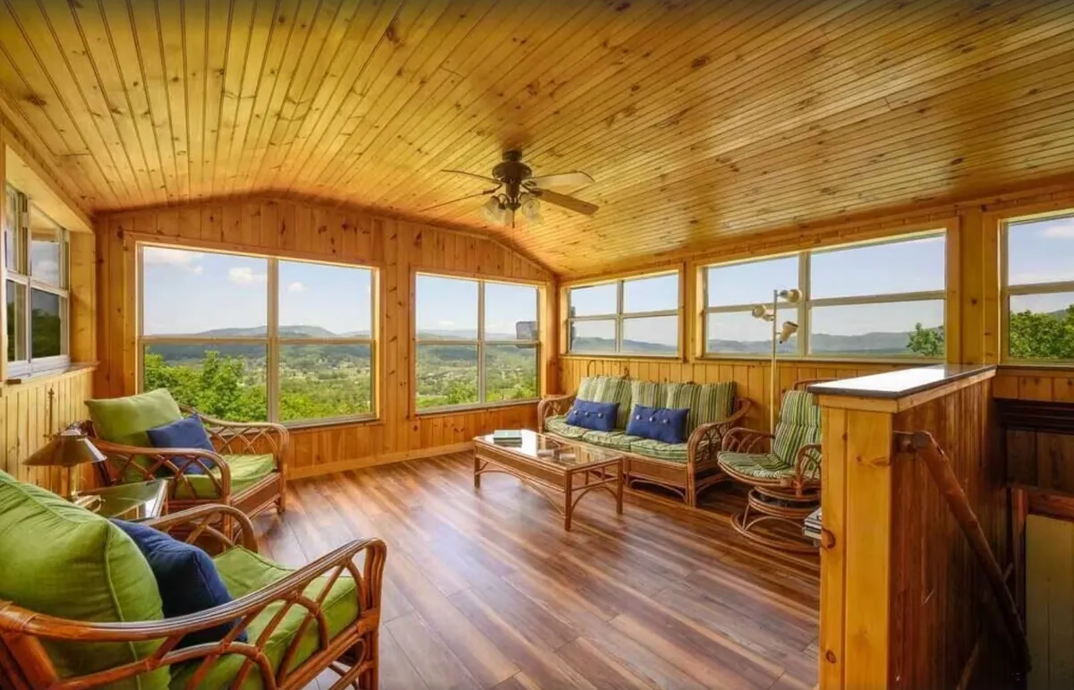A comfortable seating area beneath a wooden ceiling, with large windows framing scenic outdoor views. The space offers a peaceful ambiance, perfect for morning coffee, reading, or intimate conversations, and is bathed in natural light, highlighting its tranquil character.